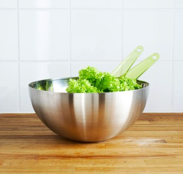 serving bowl with salad and green utensils