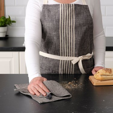 person with striped apron cleaning counter