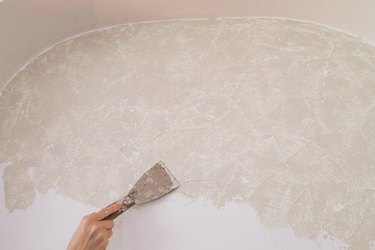Applying Roman Clay to wall with putty knife