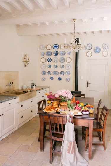 white french country style kitchen with wooden table in the center