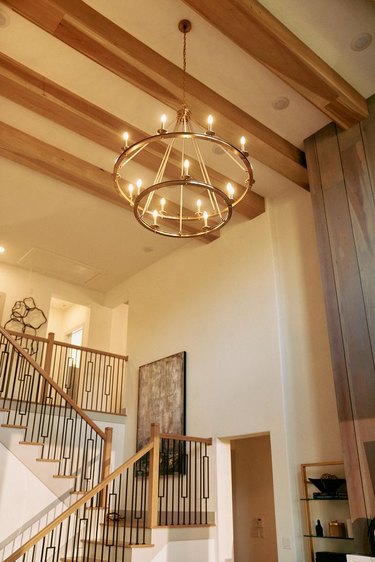 gold chandelier with exposed wooden beams and staircase