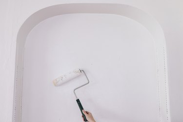 Rolling primer on built-in shelving wall with paint roller