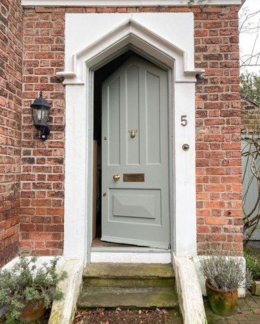 gray front door with red brick exterior