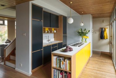Mid-century modern kitchen with black cabinets, yellow island.