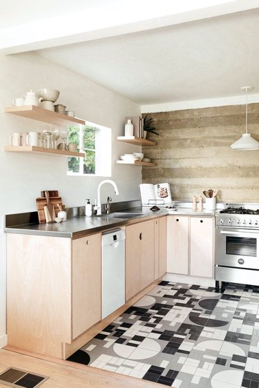 Modern kitchen with plywood cabinets, tile floor, wood backsplash.