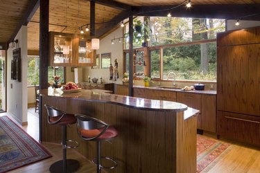 A kitchen in a post and beam-style house. The home features a lot of glass as well as wood posts and wood on the ceilings