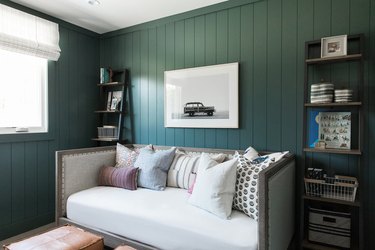 An office with a couch in which the moss green trim is the same color as the walls.