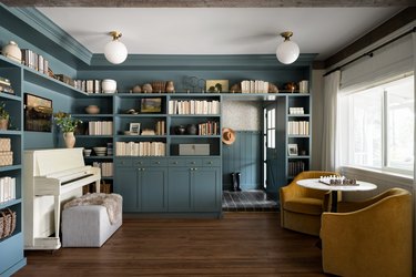 A living room with built-in bookcase and medium blue trim painted the same color as the walls.