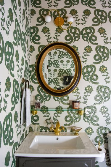 green snake patterned wallpaper and curved vanity light in traditional bathroom