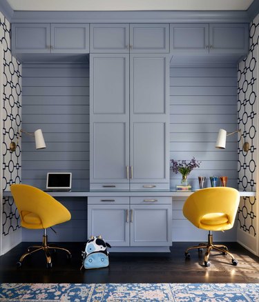office with periwinkle blue cabinets and paneling, navy and white wallpaper, and yellow desk chairs