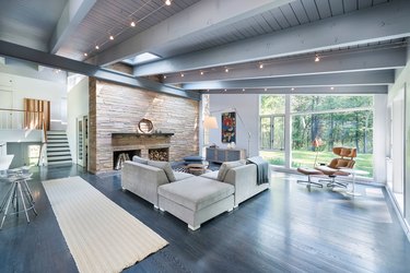 Modern gray living room with fireplace, beamed ceiling, and track lighting.