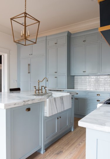 apron front white and gray marble kitchen sink in blue and white farmhouse kitchen