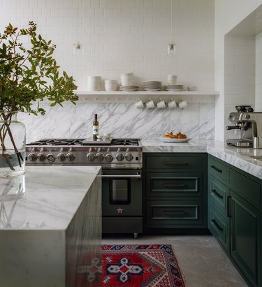 green kitchen with marble countertops and red rug