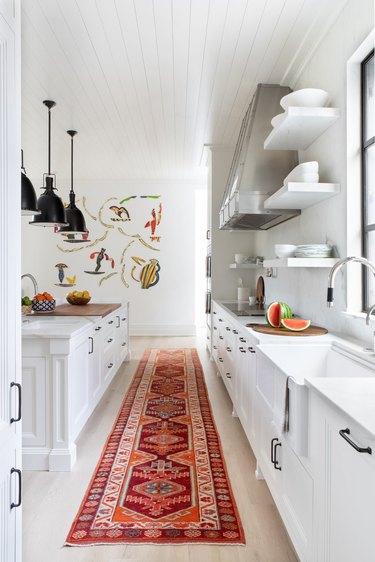 all white kitchen with orange and red rug