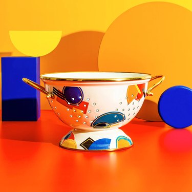 A white enamel colander with colorful, Bauhaus-inspired shapes from Darling Spring.