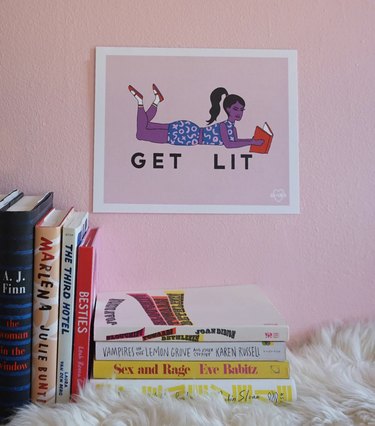A wall art print from Ash & Chess that depicts a woman reading and says 'Get Lit.'