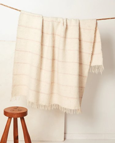 A cream-colored blanket with stripes from the textile retailer MINNA