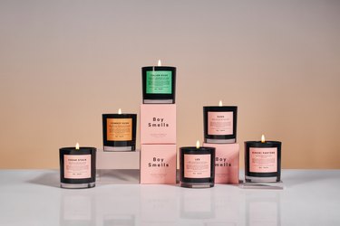 A stacked variety of burning candles from the brand Boy Smells.
