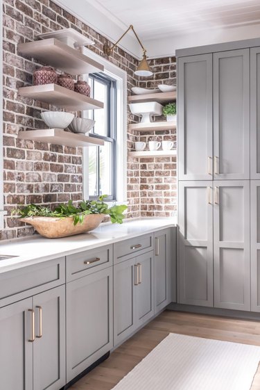 gray kitchen cabinets with brick wall
