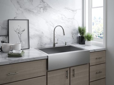 A stainless steel Kohler faucet in a gray kitchen