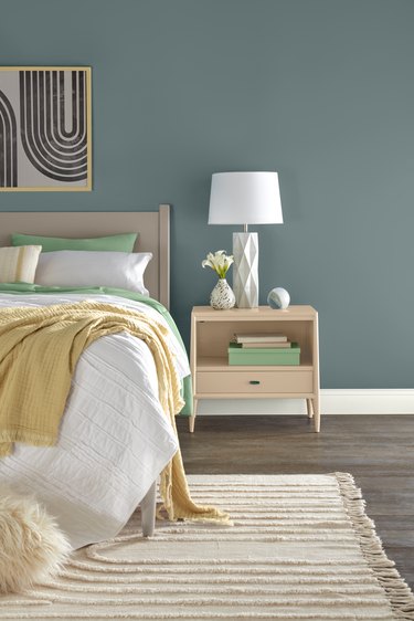 Bedroom with blue-gray walls and beige, white, yellow, and green decor