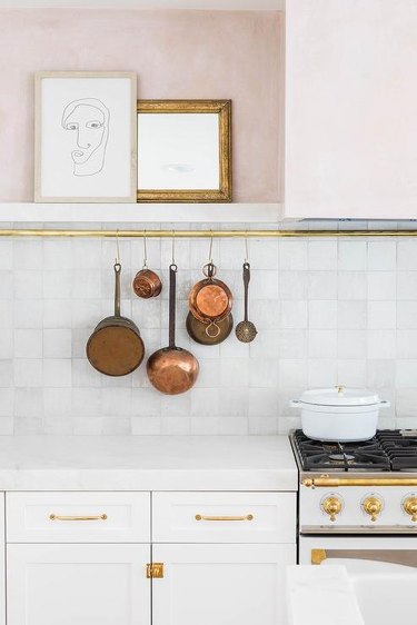 kitchen with blush and white tile walls and copper pots and pans