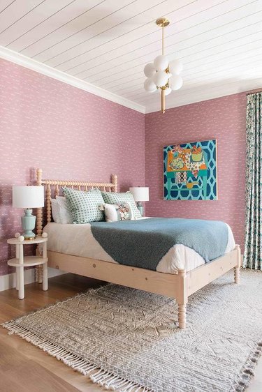 bedroom with pink walls and seafoam green lamp and pillows