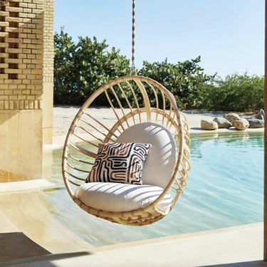 hanging rattan egg chair in front of pool