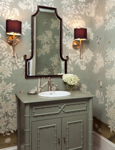 bathroom with seafoam green walls and vanity and maroon sconces