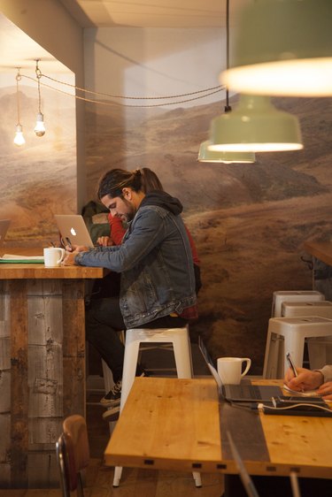 Interior of cafe with a person wearing a jean jacket sitting on a white stool