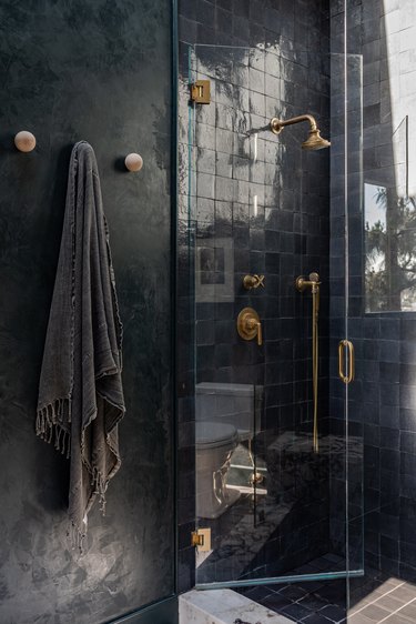 black shower with black zellige tiles and brass hardware