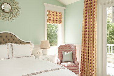 bedroom with seafoam green walls and orange curtains