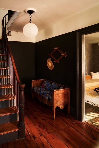dark wood staircase surrounded by entryway with black walls and white ceiling