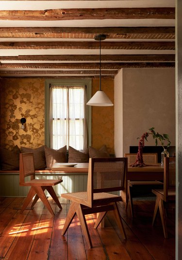 gold wallpaper in the dining room with sage green accents and wood ceiling rafters