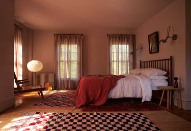 primary bedroom with pink painted walls and checkered rugs
