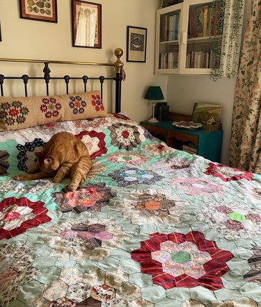 bedroom with vintage quilt and orange cat on bed