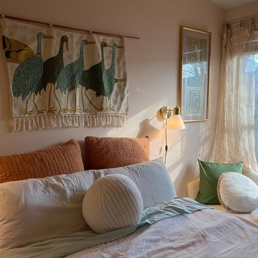 bedroom with thrifted pillows and bird wall hanging
