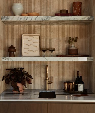 bar area with marble shelves and a gold faucet