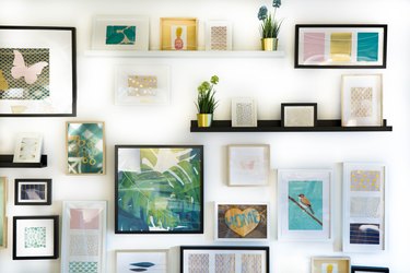 Gallery wall of turquoise, yellow, and pink art in frames of different sizes