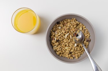 bowl of cereal with nuts and raisins and orange juice