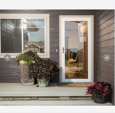 Full-view aluminum storm door on front porch. Potted plants sit to the left of the door
