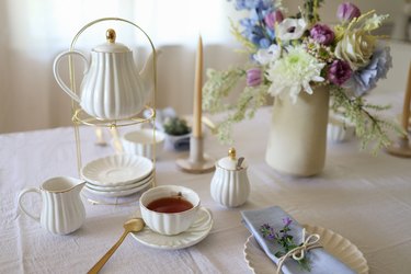 White fluted teapot with teacup full of black tea