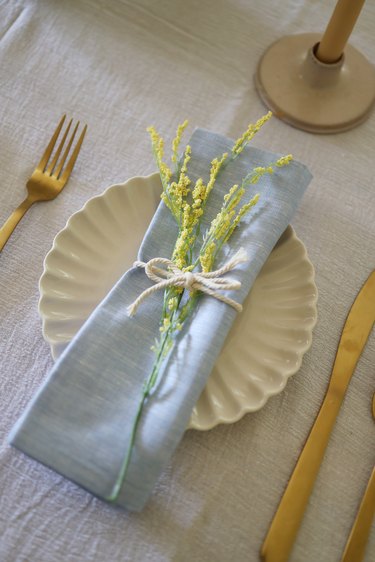 Blue chambray napkin on plate with yellow flowers tied on top