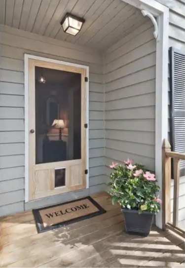 Photo of an unfinished screen door with pet door on the bottom and welcome mat