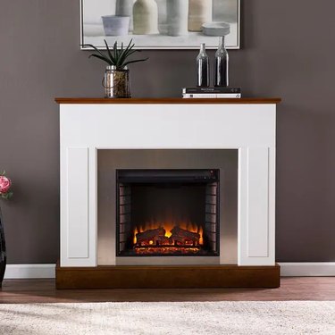 A white portable electric fireplace in a room with gray walls
