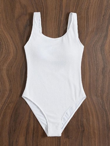 A white one-piece bathing suit on a wood table