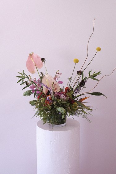 floral arrangement on a stand with light pink wall in the background