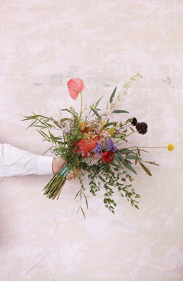 person's arm and hand holding a floral arrangement