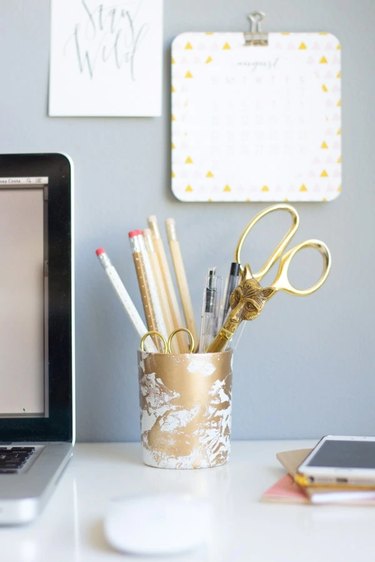 gold and white marbled pencil cup with office essentials at gray and white workstation