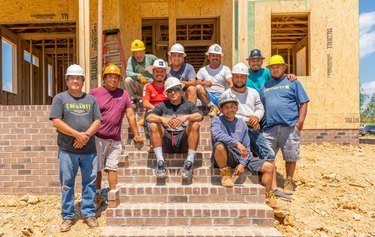 group of construction workers on steps near a house under construction